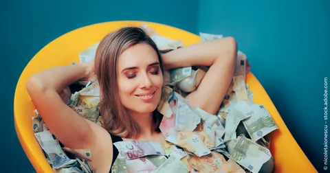Eine Frau genießt die finanzielle Freiheit in einer Badewanne voller Geldscheine