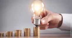 Der Cost-Average-Effekt einfach erklärt Das Bild steht symbolisch für den Cost-Average-Effekt mit Münzstapeln als Sparraten und einer Glühbirne